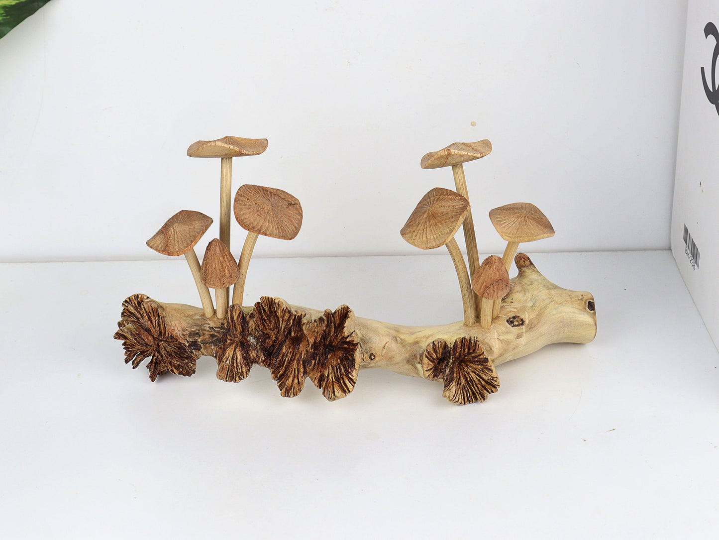 Hand-carved natural wooden sculpture featuring multiple fanned and pleated mushrooms growing horizontally on a long, textured wood log or root, rustic tabletop decor.