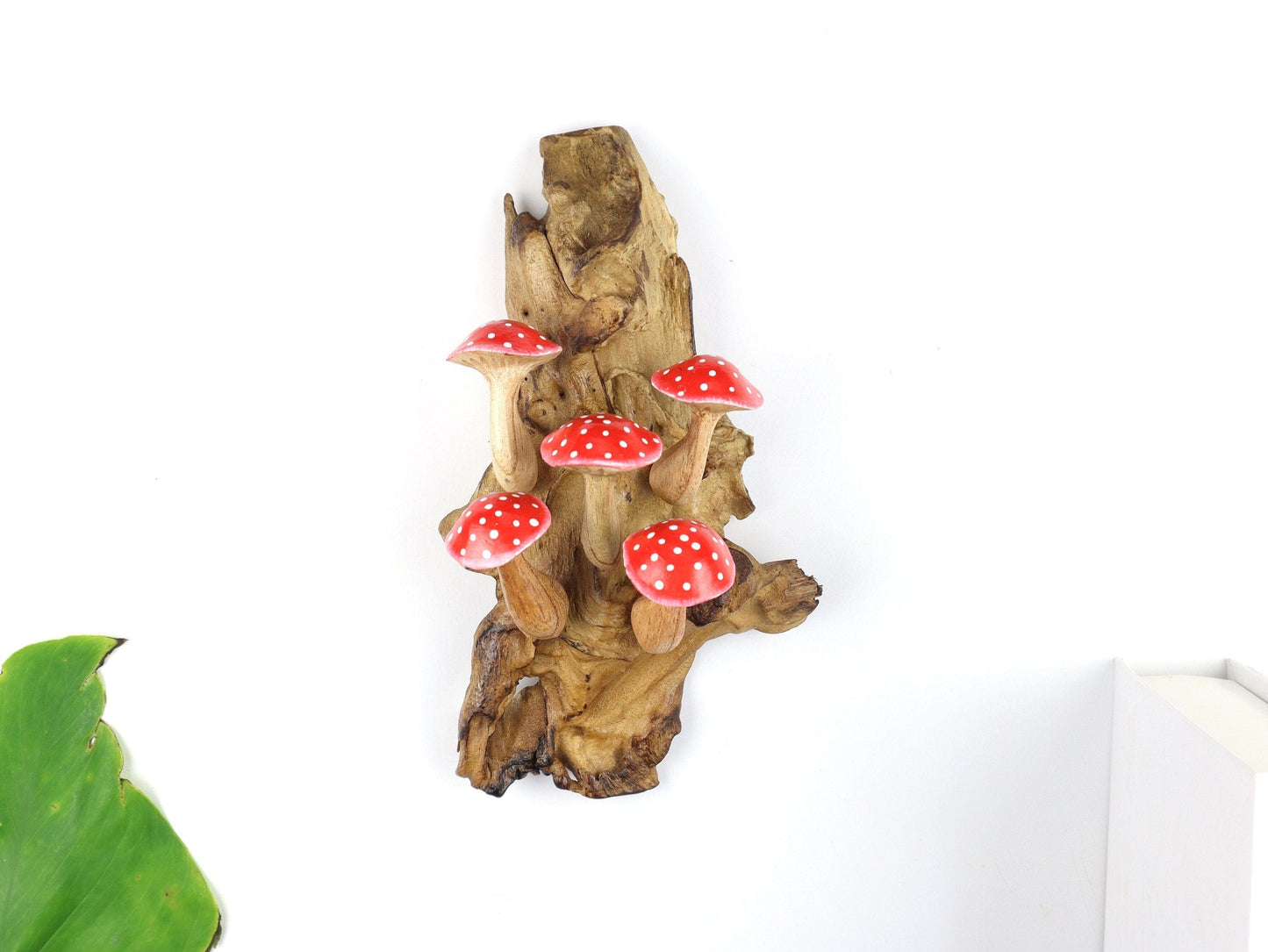 Hand-carved natural wooden wall art featuring five red and white polka-dot mushrooms on an upright natural wood log or root, whimsical fairy tale decor.