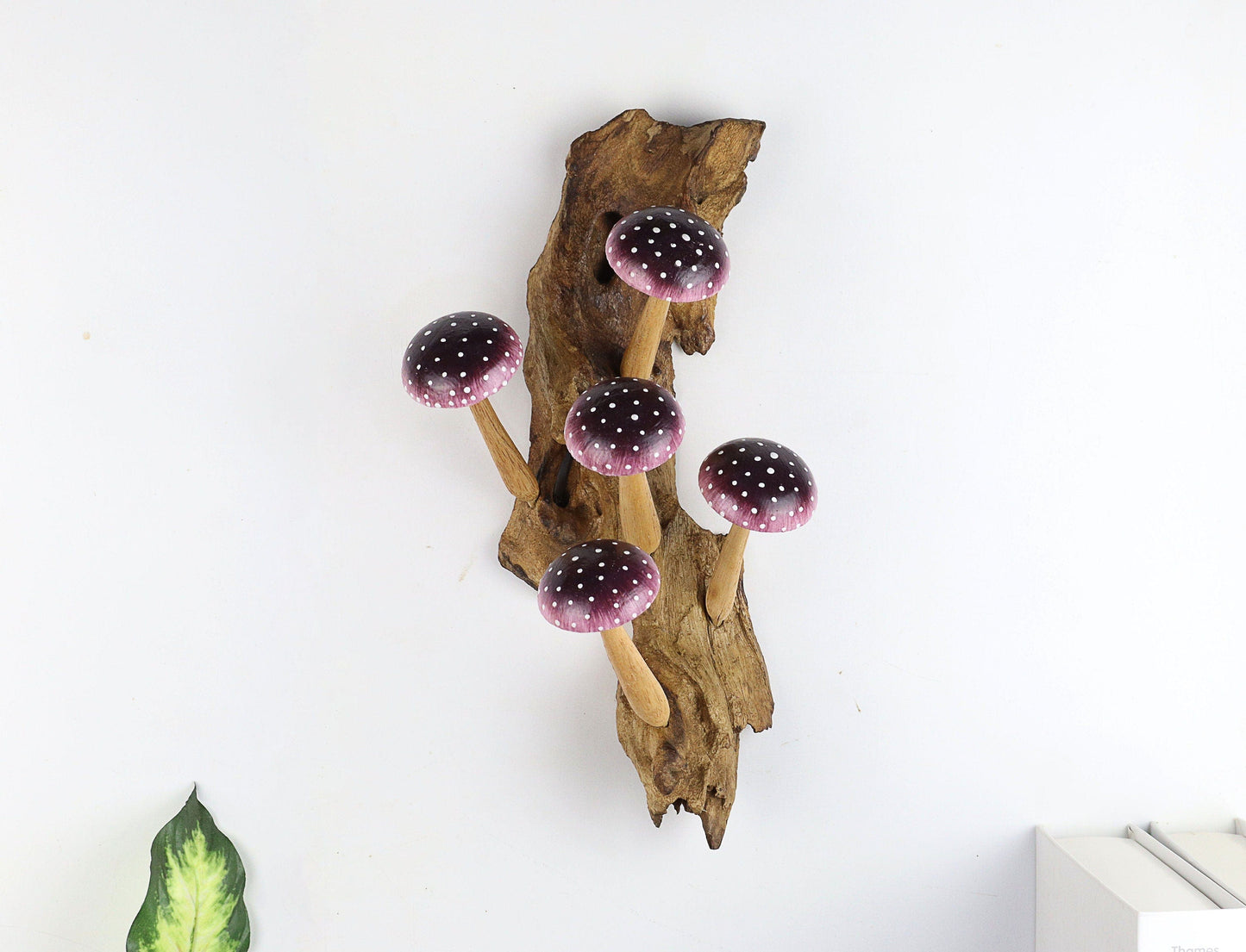Hand-carved natural wooden wall art featuring five purple and white polka-dot mushrooms on an upright natural wood log or root, whimsical fairy tale decor.