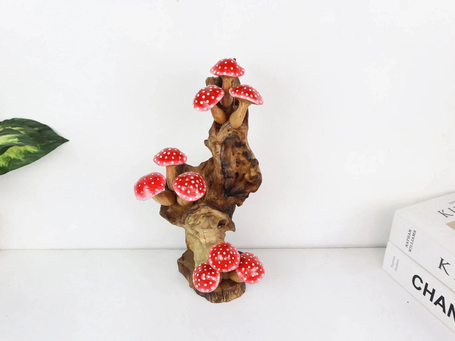 Hand-carved natural wooden sculpture featuring a dense cluster of red and white polka-dot mushrooms on an upright natural wood log or root, whimsical tabletop decor.