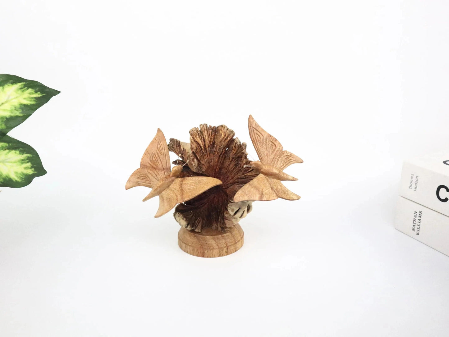 Hand-carved natural wooden sculpture featuring a pair of butterflies on a textured pine cone, mounted on a round freestanding wooden base, rustic insect decor.
