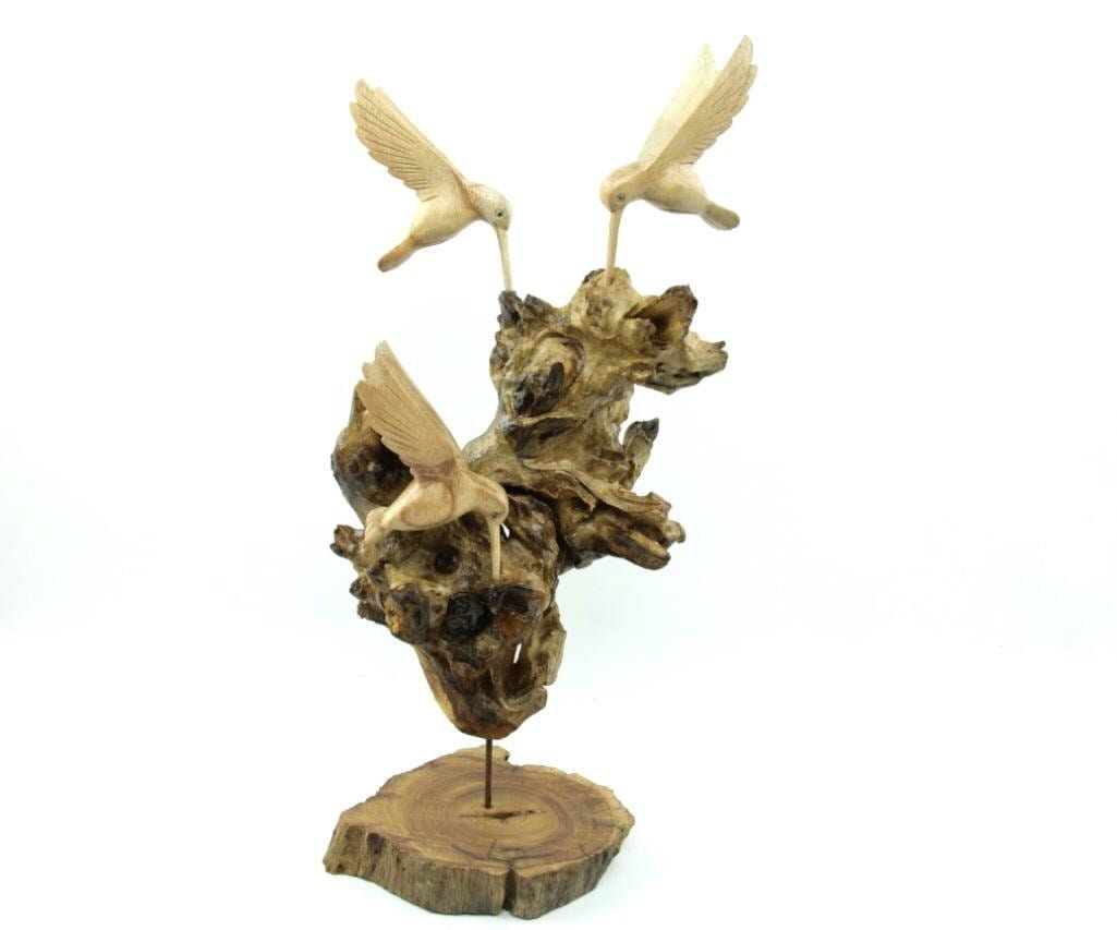 Hand-carved natural wooden sculpture featuring three hummingbirds in flight around a gnarled wood base, mounted on a round freestanding wooden base, rustic bird decor.