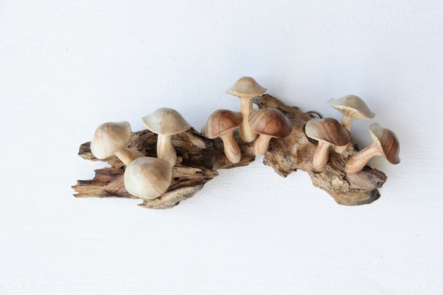 Hand-carved natural wooden sculpture featuring multiple smooth-capped mushrooms sprouting horizontally from a wood log or root, rustic woodland decor.