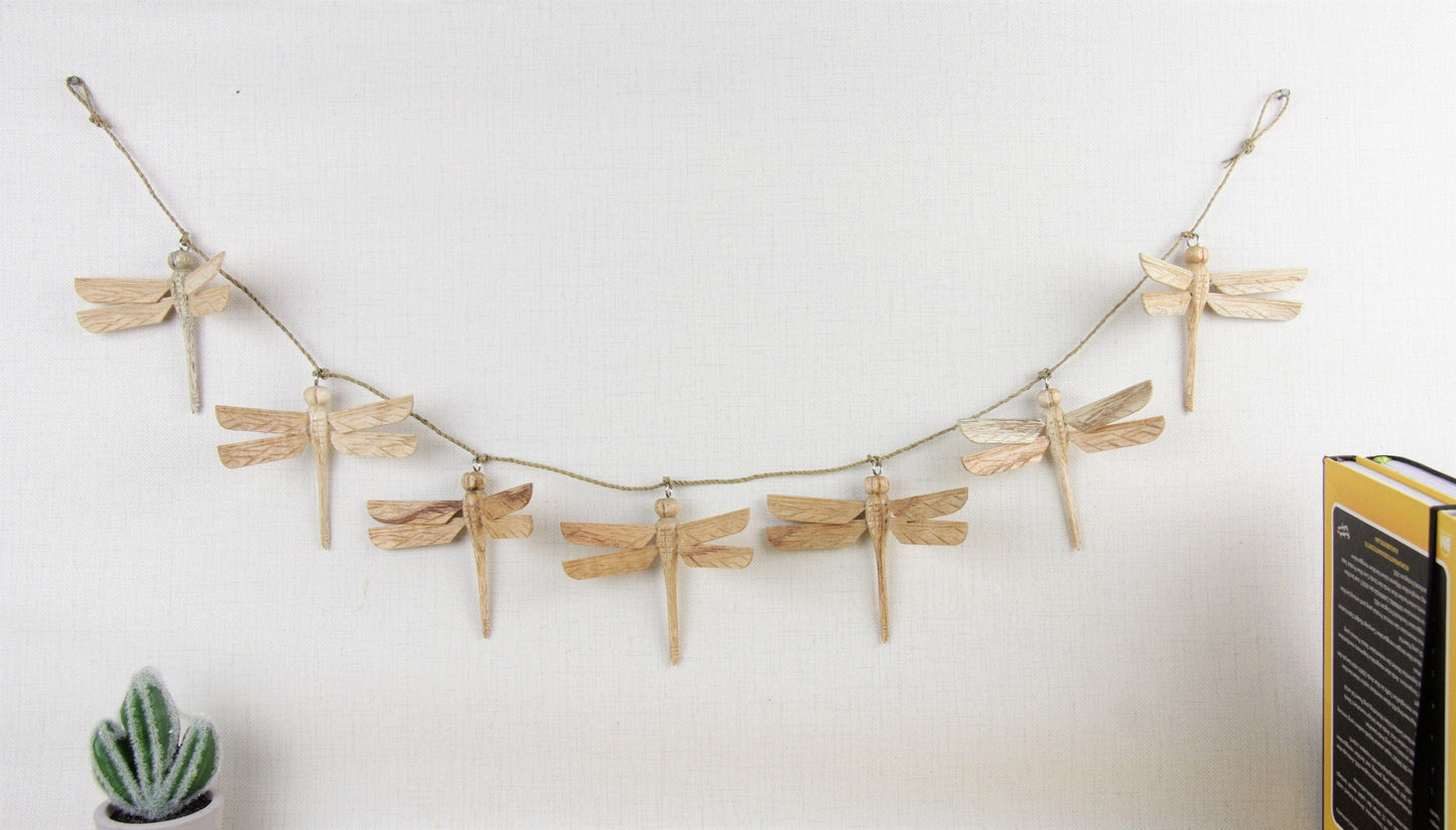 Hand-carved natural wooden garland with multiple dragonflies strung on a twine, rustic wall hanging decor.