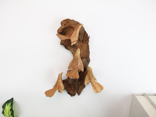 Hand-carved natural wooden wall art featuring four Canary birds interacting with a gnarled wood base, rustic bird flock decor.