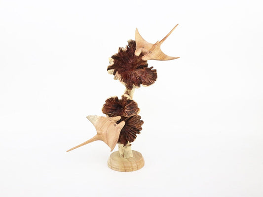 Hand-carved natural wooden sculpture featuring two manta rays swimming around textured wood pods, mounted on a round wooden base, rustic marine life decor.