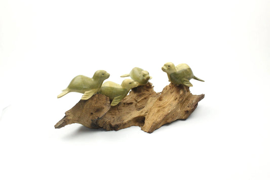 Hand-carved natural wooden sculpture featuring a group of four seals resting on a rugged driftwood base, rustic coastal decor.