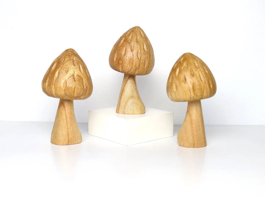 Hand-carved natural wooden sculpture of a single mushroom with a conical cap and thick stem, minimalist tabletop decor.