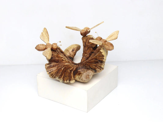 Hand-carved natural wooden sculpture featuring three unpainted bees on a low, gnarled horizontal wood base, rustic tabletop decor.