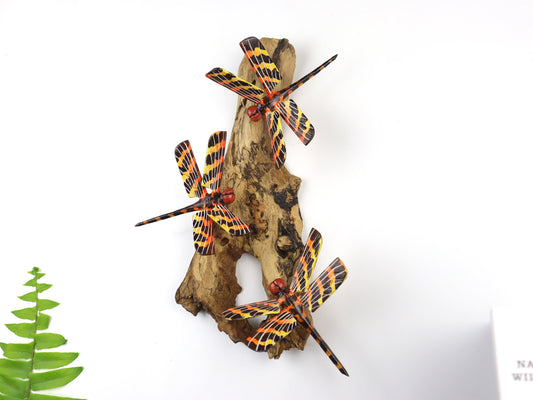 Hand-carved and painted wooden wall art featuring three vibrant orange and yellow striped dragonflies on a vertical gnarled wood base, rustic bird decor.