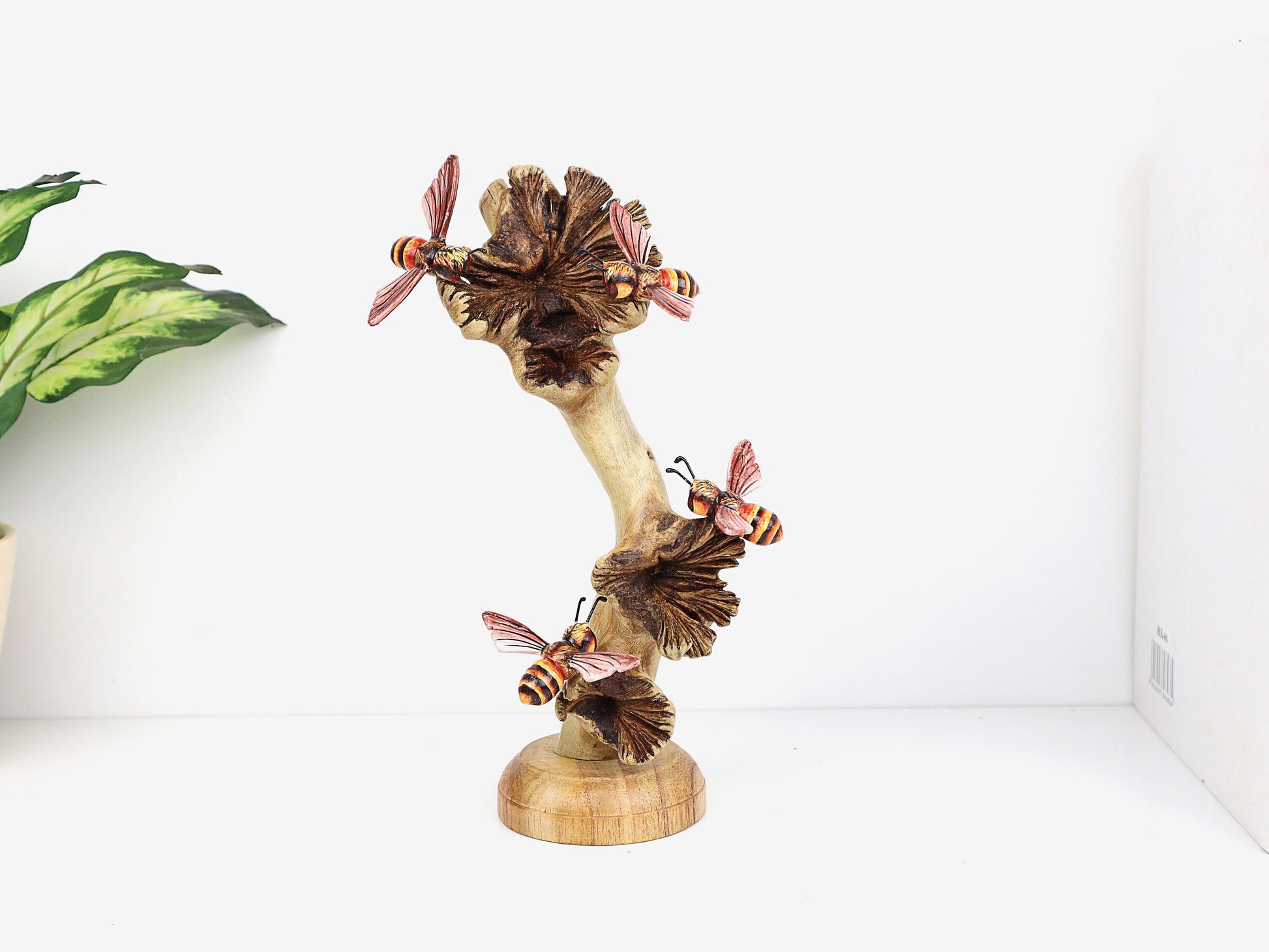 Hand-carved and painted wooden sculpture featuring four bees with orange and black striped bodies on mushroom-like elements, on a rustic wood base, tabletop decor.