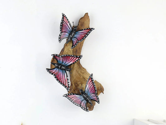Hand-carved and painted wooden wall art featuring three multi-colored butterflies on a gnarled upright wood branch, rustic decor.