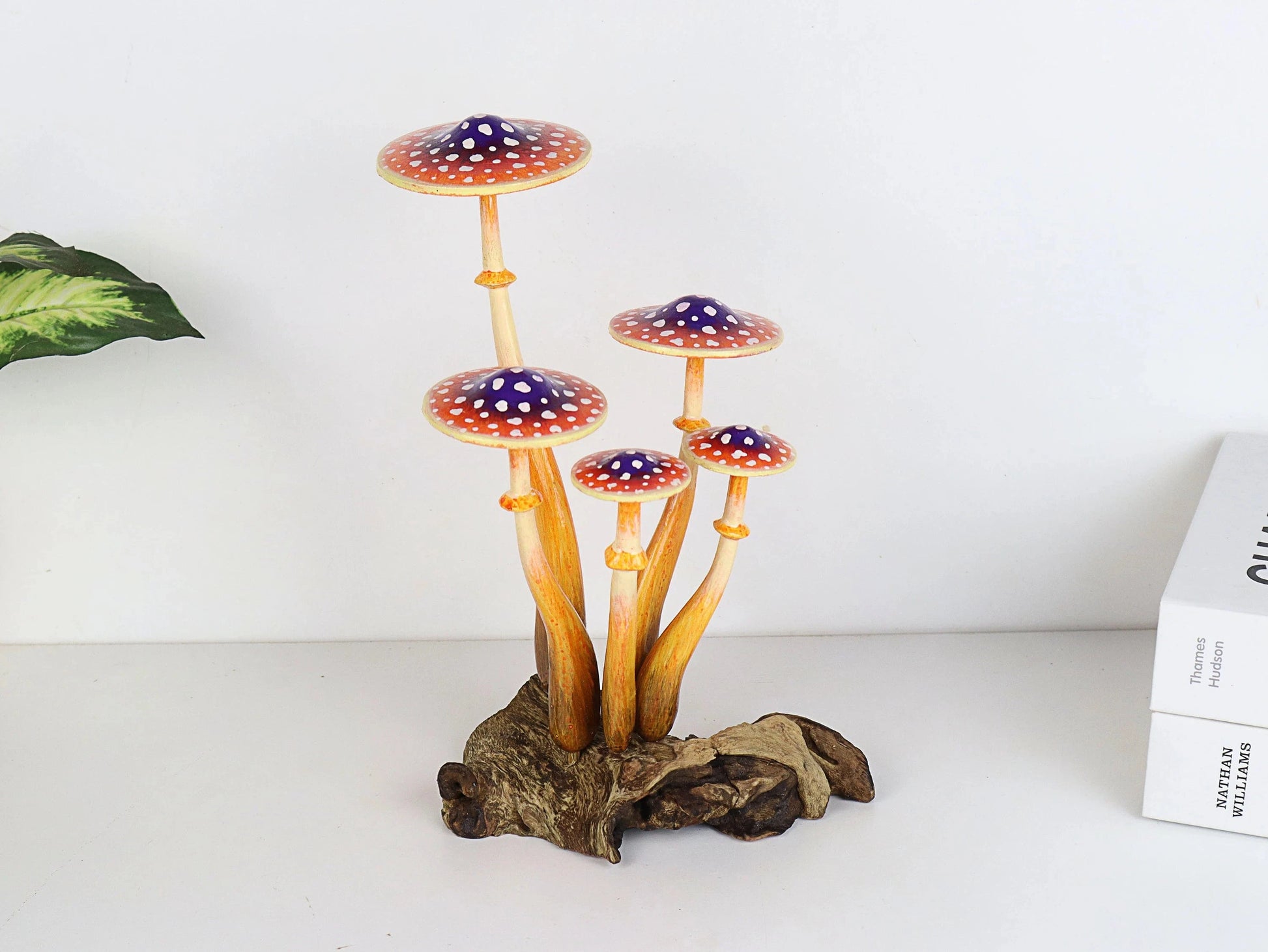Hand-carved wooden mushroom sculpture with a cluster of five orange and purple caps with white polka dots and long stems on a rustic wood base, whimsical tabletop decor.