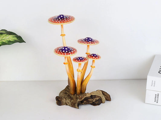 Hand-carved wooden mushroom sculpture with a cluster of five orange and purple caps with white polka dots and long stems on a rustic wood base, whimsical tabletop decor.
