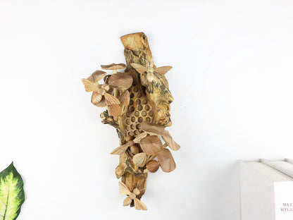 Hand-carved natural wooden wall art featuring bees and mushrooms on a carved honeycomb-like pattern on a gnarled upright wood log, rustic bee and fungus decor.

