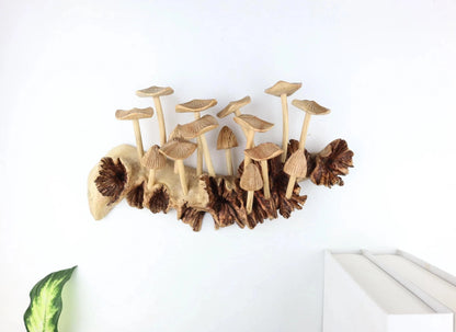 Hand-carved natural wooden sculpture featuring multiple fanned and pleated mushrooms growing horizontally on a low, rugged wood log or root, rustic tabletop centerpiece.