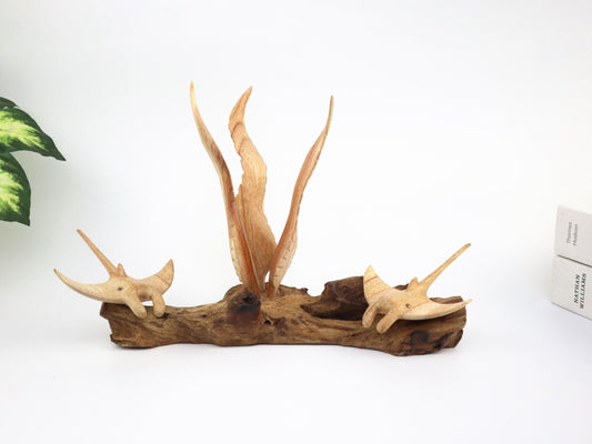 Hand-carved natural wooden sculpture featuring a pair of manta rays swimming around a central seaweed-like wood carving on a rugged driftwood base, rustic coastal decor.