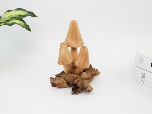 Hand-carved natural wooden sculpture featuring a small cluster of three conical mushrooms sprouting from a rugged wood root, rustic tabletop decor.