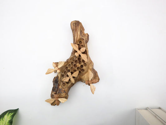 Hand-carved natural wooden wall art featuring five bees on a carved honeycomb-like pattern on a gnarled upright wood log, rustic bee decor.