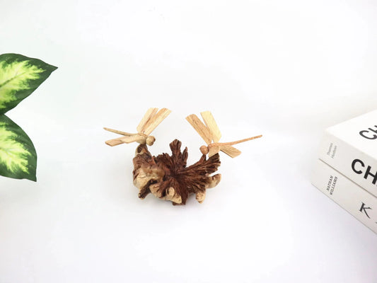 Hand-carved natural wooden sculpture featuring a pair of dragonflies on a textured wood piece, mounted on a round freestanding wooden base, rustic insect decor.