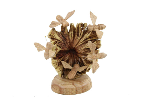 Hand-carved natural wooden sculpture featuring multiple bees swarming around a stylized flower, mounted on a round freestanding wooden base, rustic garden decor.

